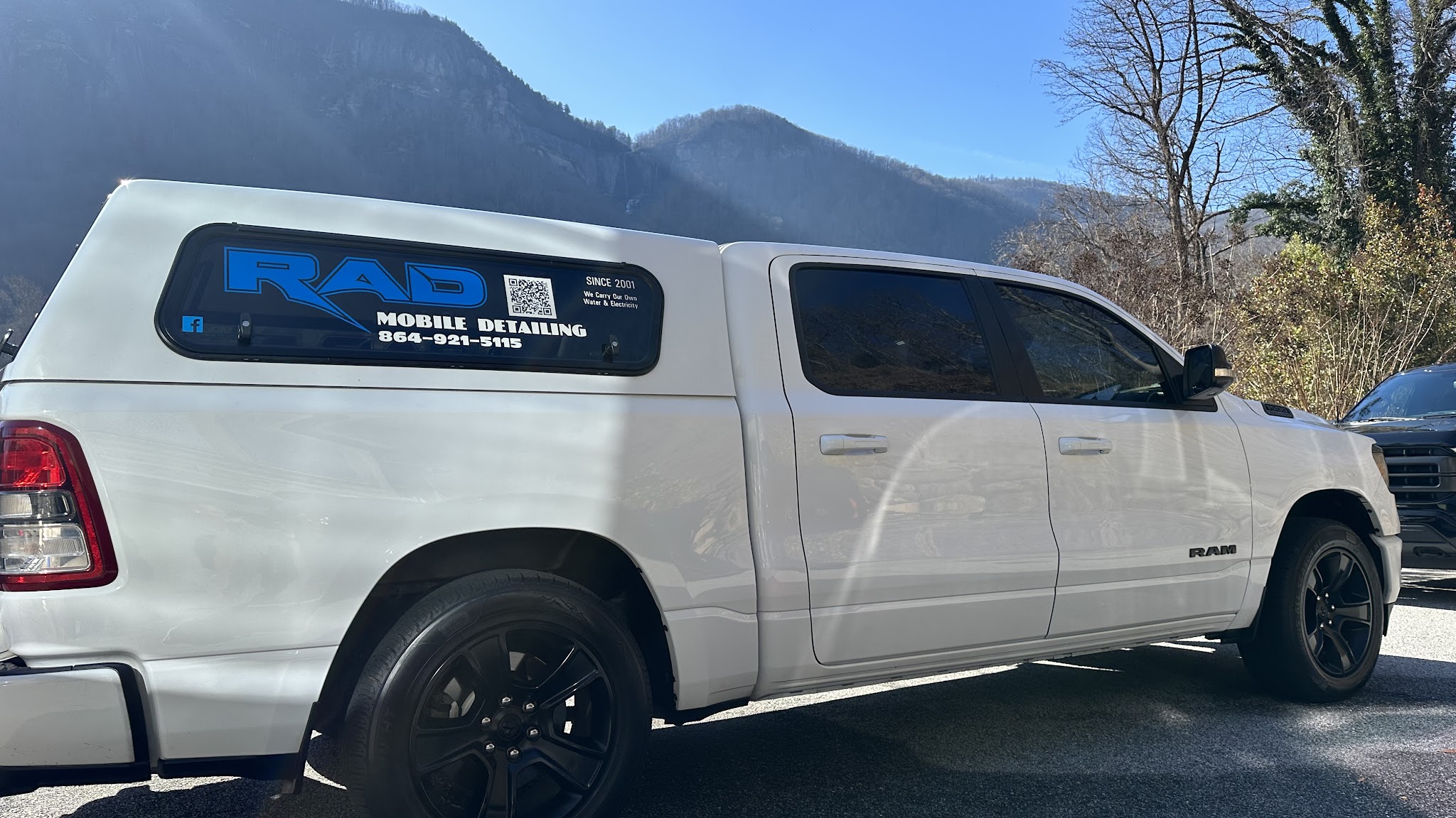 The RAD Mobile Detailing truck with its window signage, parked below a mountain