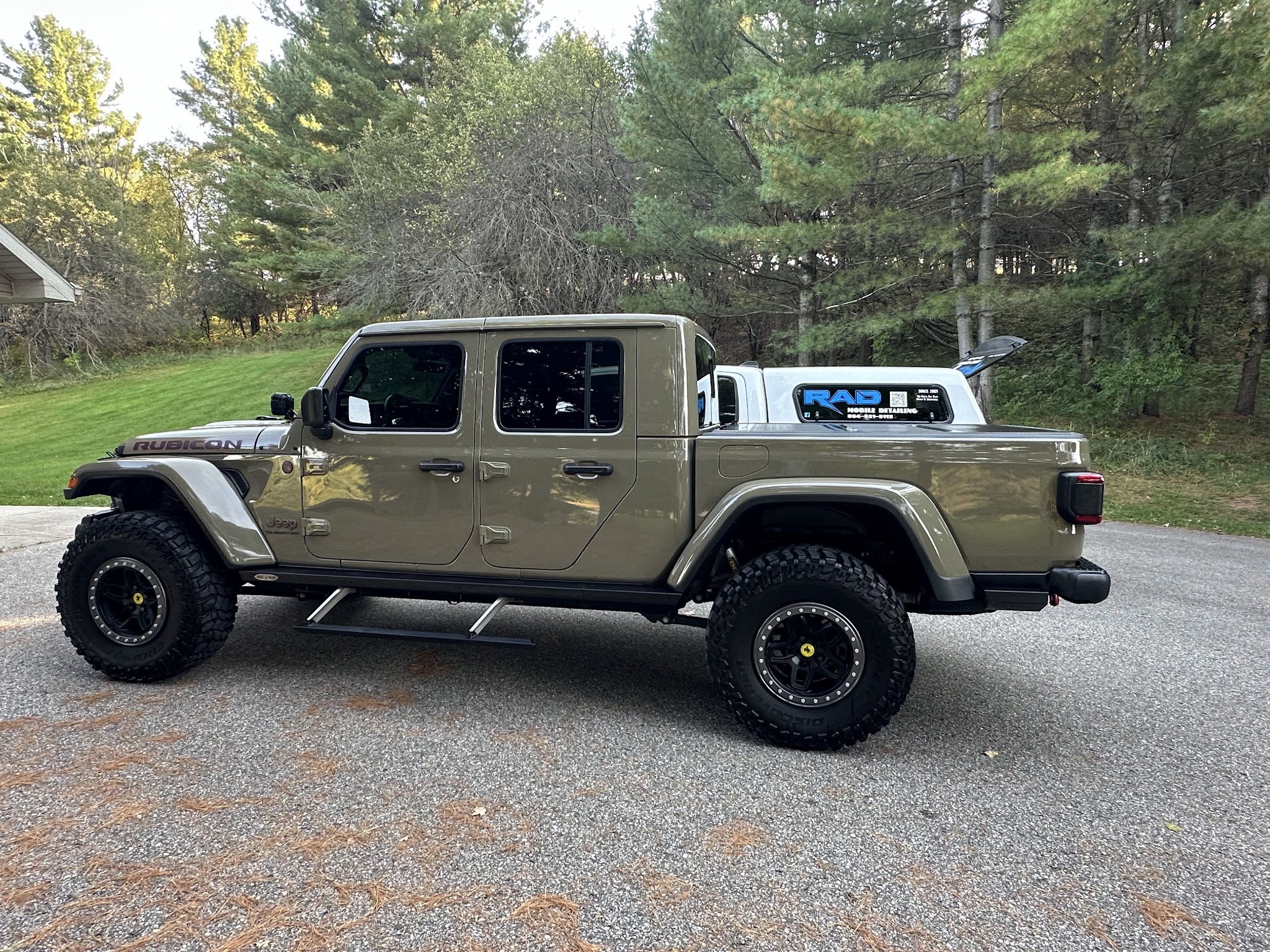 A Jeep Gladiator on gravel with the RAD truck behind it