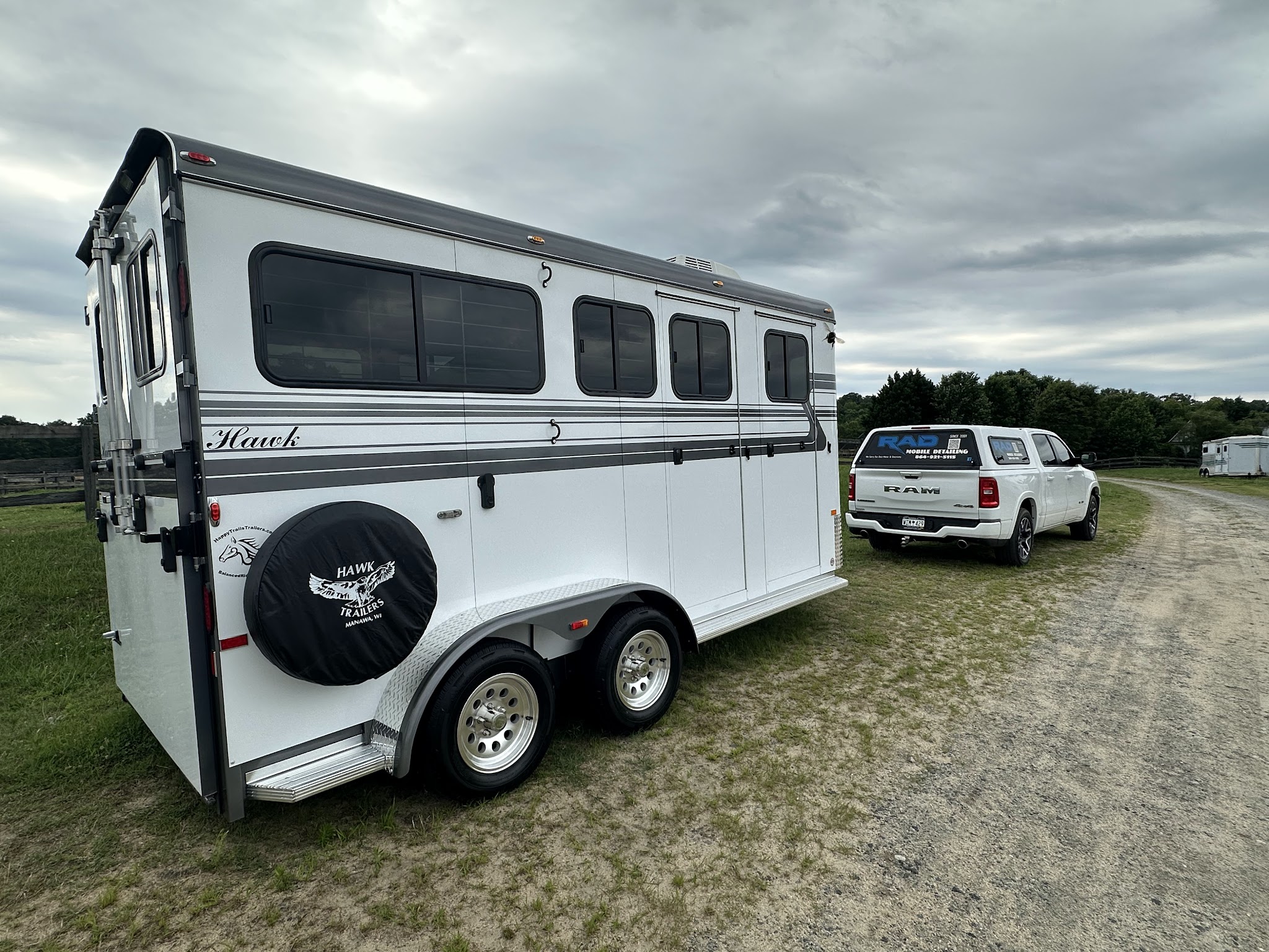 A white horse trailer parked in a field